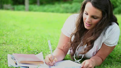 stock-footage-brunette-woman-writing-on-notebooks-in-a-park